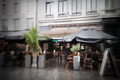an outdoor cafe with tables and chairs and umbrellas at Luxury Suites Grotemarkt by Rikas Hotels in Antwerp