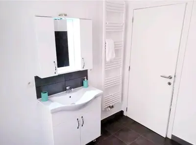 a white bathroom with a sink and a mirror at City Brussels Apartments in Brussels