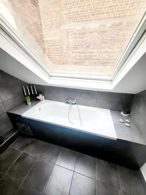 a large bath tub in a room with a brick wall at City Brussels Apartments in Brussels
