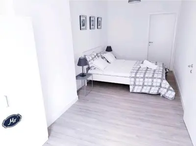 a white bedroom with a bed and a table at City Brussels Apartments in Brussels