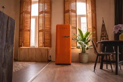an orange refrigerator in a room with windows at SLEEP INN - 1001 Nights Loft Citycenter with Balconyview in Antwerp