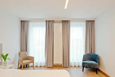 a bedroom with a bed and a chair and windows at Hotel Den Briel in Ghent