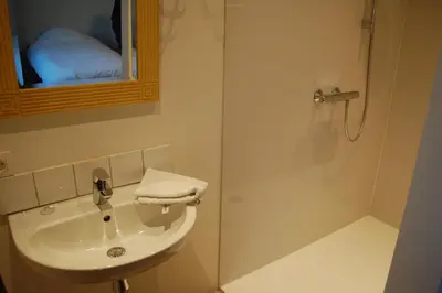 a bathroom with a sink and a shower with a mirror at Hoppernachten in Zele