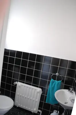 a black tiled bathroom with a toilet and a sink at Hoppernachten in Zele