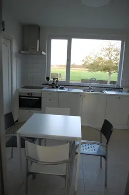 a kitchen with a table and chairs and a window at Hoppernachten in Zele