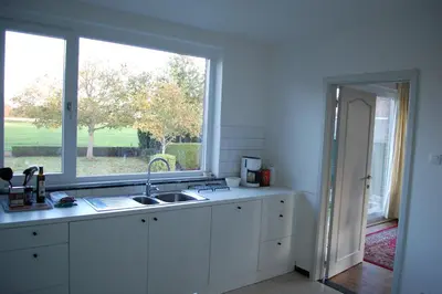 a white kitchen with a sink and a window at Hoppernachten in Zele