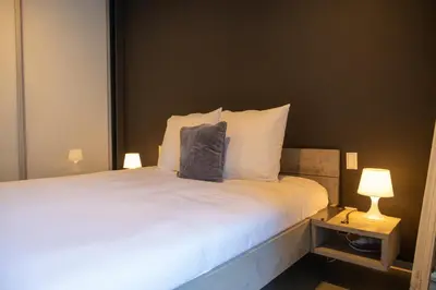 a bedroom with a large white bed with two lamps at London 993 Apt 202 in Antwerp