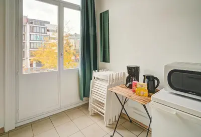a kitchen with a microwave and a table and a window at Theodore Residence in the Heart of Antwerp in Antwerp