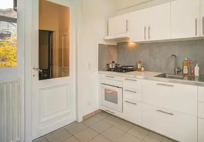 a kitchen with white cabinets and a sink at Theodore Residence in the Heart of Antwerp in Antwerp
