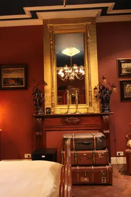 a bedroom with a bed and a mirror and suitcases at B&B De Lachende Engel in Mechelen