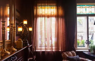 a room with a window with curtains and a chair at B&B De Lachende Engel in Mechelen