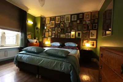 a bedroom with a bed with pictures on the wall at B&B De Lachende Engel in Mechelen