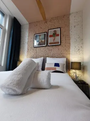 a bedroom with a large bed with white sheets and pillows at SHWAY - The Pink Pigeon in Antwerp