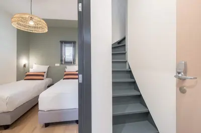 a bedroom with two beds and a staircase at SHWAY - The Pink Pigeon in Antwerp
