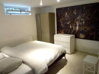 a bedroom with a white bed and a painting on the wall at Comfortable Apartment in Waterloo with Jacuzzi - 78m² in Waterloo