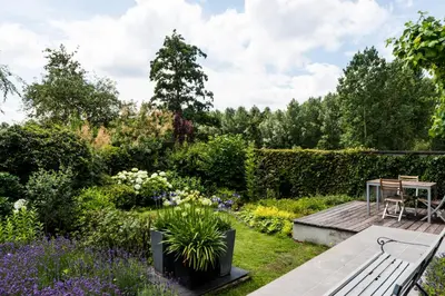 a garden with a wooden bench and flowers at B&B Hier en Nu in Heusden