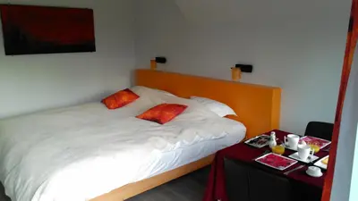 a bedroom with a bed with white sheets and orange pillows at B&B Hier en Nu in Heusden