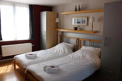 two beds in a room with white sheets at Brussels BnB in Brussels