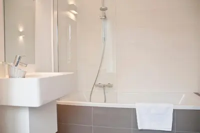 a white bathroom with a sink and a bath tub at Domein Martinus in Halle