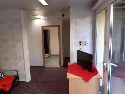a room with a tv on a podium with a red table at casa di Gino in Antwerp