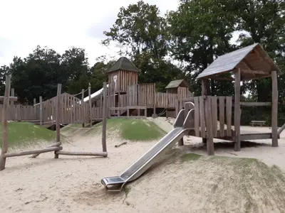 a wooden playground with a slide in the sand at casa di Gino in Antwerp