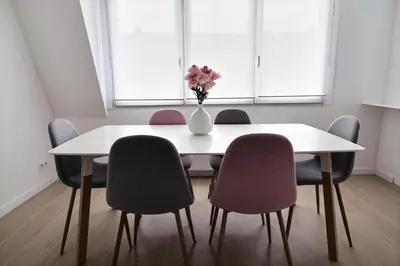 a white table with chairs and a vase of flowers on it at Rent a flat - Montgomery in Brussels