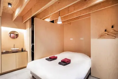 a bedroom with a bed with two red towels on it at Juno Boat in Ghent