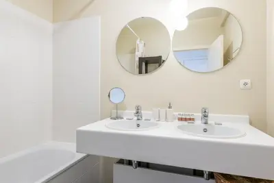 a white bathroom with two sinks and two mirrors at EU Parliament Terrace Residence in Brussels