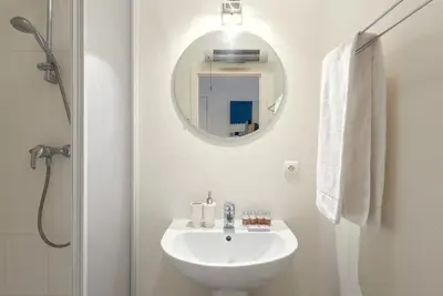 a white bathroom with a sink and a mirror at EU Parliament Terrace Residence in Brussels