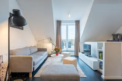 a living room with a couch and a tv at Flagey Penthouse Duplex in Brussels