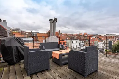 a patio with chairs and a table on a roof at Flagey Penthouse Duplex in Brussels