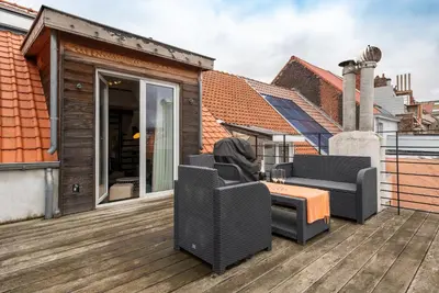 a patio with two chairs and a table on a deck at Flagey Penthouse Duplex in Brussels