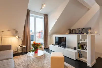 a living room with a couch and a tv at Flagey Penthouse Duplex in Brussels