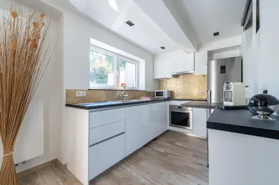a kitchen with white cabinets and black counter tops at COZY APARTMENT IN BRUSSELS in Brussels