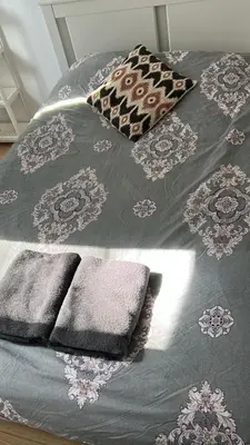 a bed with a gray comforter and three towels at Best nest in Brussels