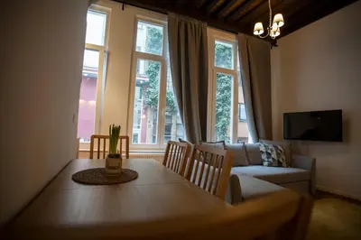a living room with a table and a couch and windows at Luxury Suites Riverside Residence by Rikas Hotels in Antwerp