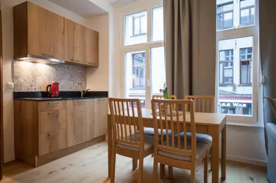 a kitchen with a table and two chairs and a kitchen with windows at Luxury Suites Riverside Residence by Rikas Hotels in Antwerp