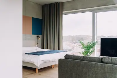 a bedroom with a bed and a couch and a large window at De Hoorn in Leuven