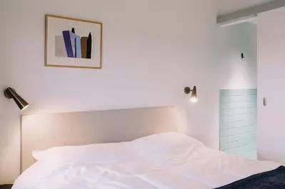a bedroom with a white bed and a picture on the wall at De Hoorn in Leuven