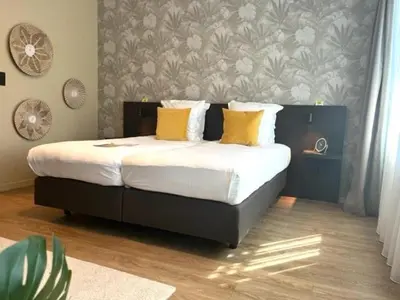 a bedroom with a large bed with yellow pillows at Bloomhotel in Lochristi