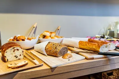 a table with different types of bread and other foods at Bloomhotel in Lochristi