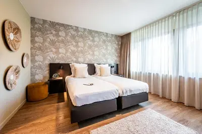 a bedroom with a large bed and a large window at Bloomhotel in Lochristi