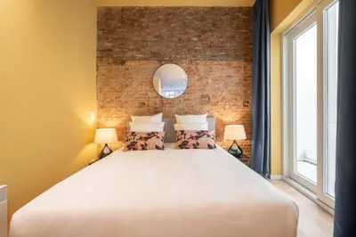 a bedroom with a large white bed with a brick wall at SHWAY - The Red Monkey in Antwerp