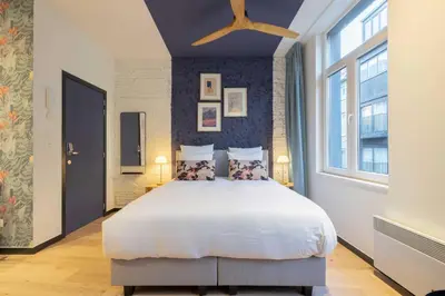 a bedroom with a large bed and a large window at SHWAY - The Blue Parrot in Antwerp