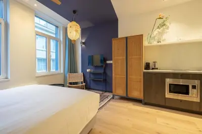 a bedroom with a large bed and a kitchen at SHWAY - The Blue Parrot in Antwerp