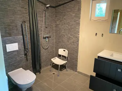 a bathroom with a shower and a toilet and a chair at De Kasseihoeve in Kalken