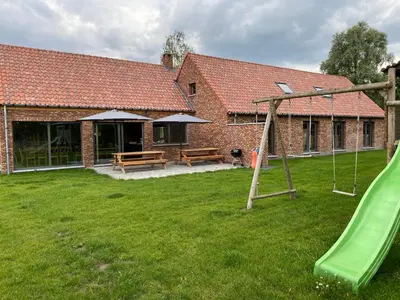 a house with a playground with a slide at De Kasseihoeve in Kalken