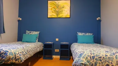 a room with two beds and a blue wall at Hotel Amethist in Ramsel