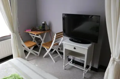 a living room with a television and a table with chairs at B&B Den Boskant in Zandbergen