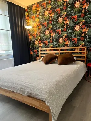 a bed in a bedroom with a floral wall at Elma’s Place in Ghent